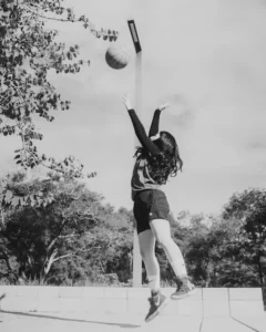 Woman playing basketball on an outdoor court.