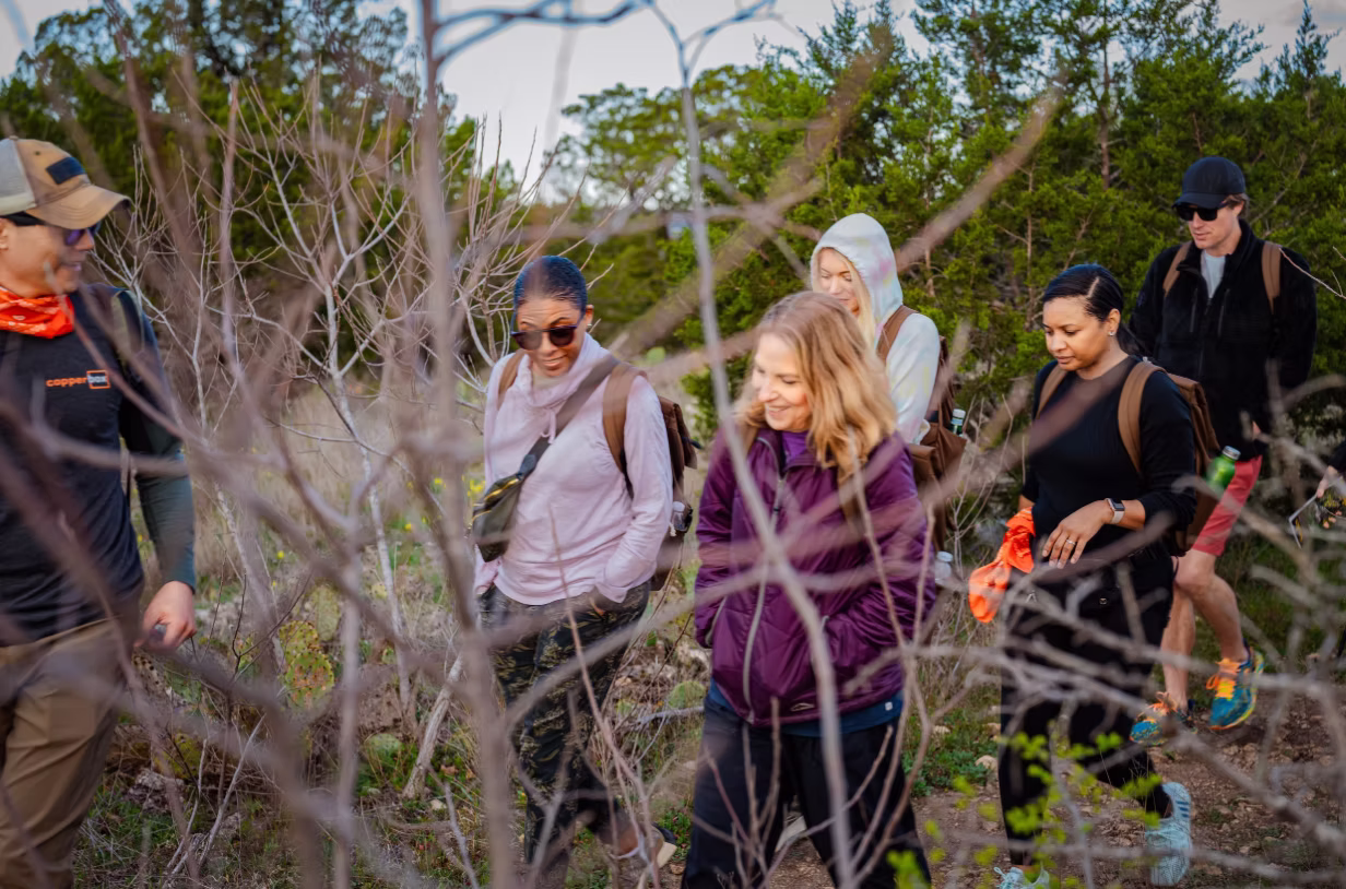 SXSW attendees walking together through a nature trail during the Copperbox LLC leadership and networking activation outside Austin, Texas.