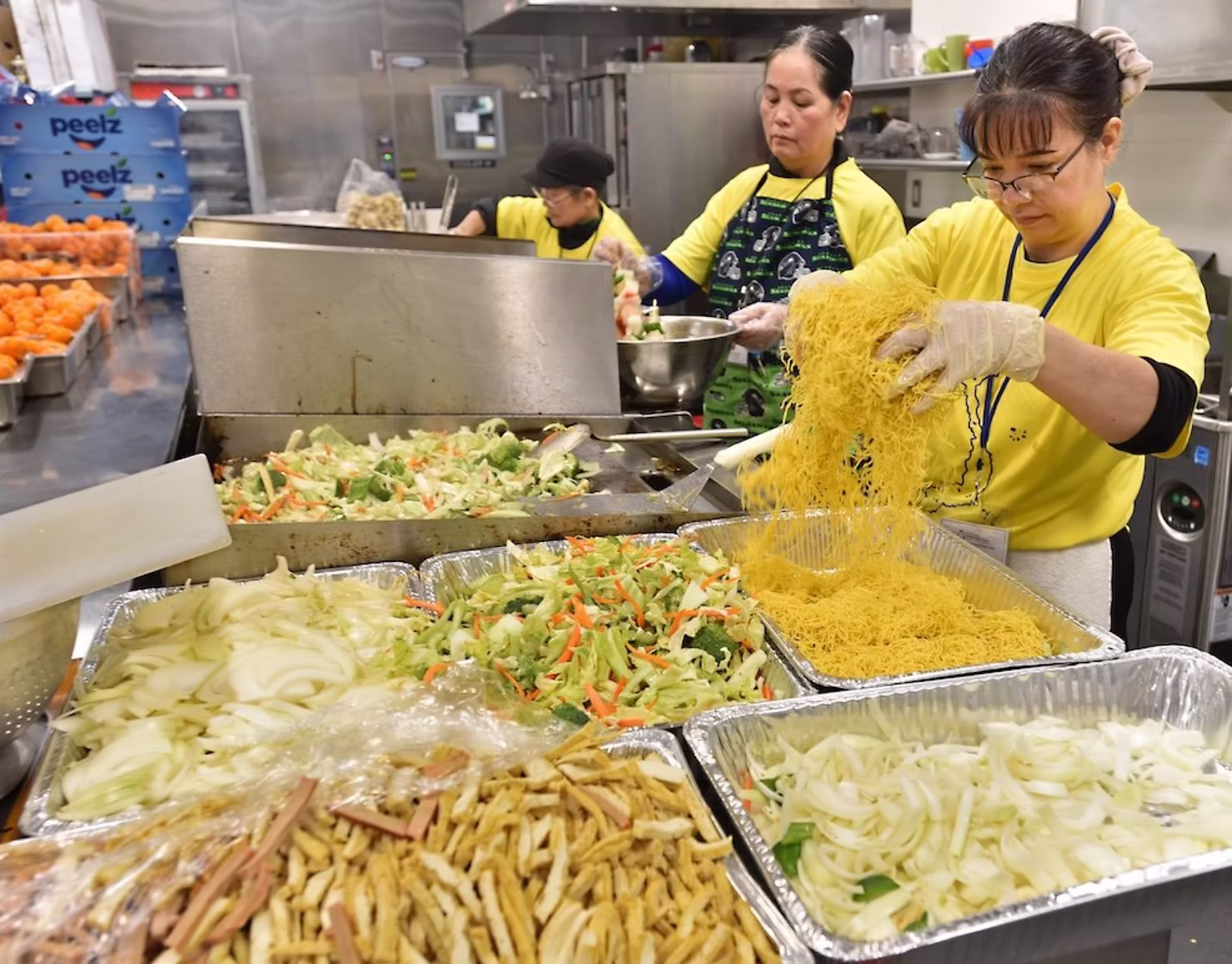 Volunteers preparing traditional Vietnamese dishes and noodles in a kitchen during a Tet Lunar New Year community celebration.