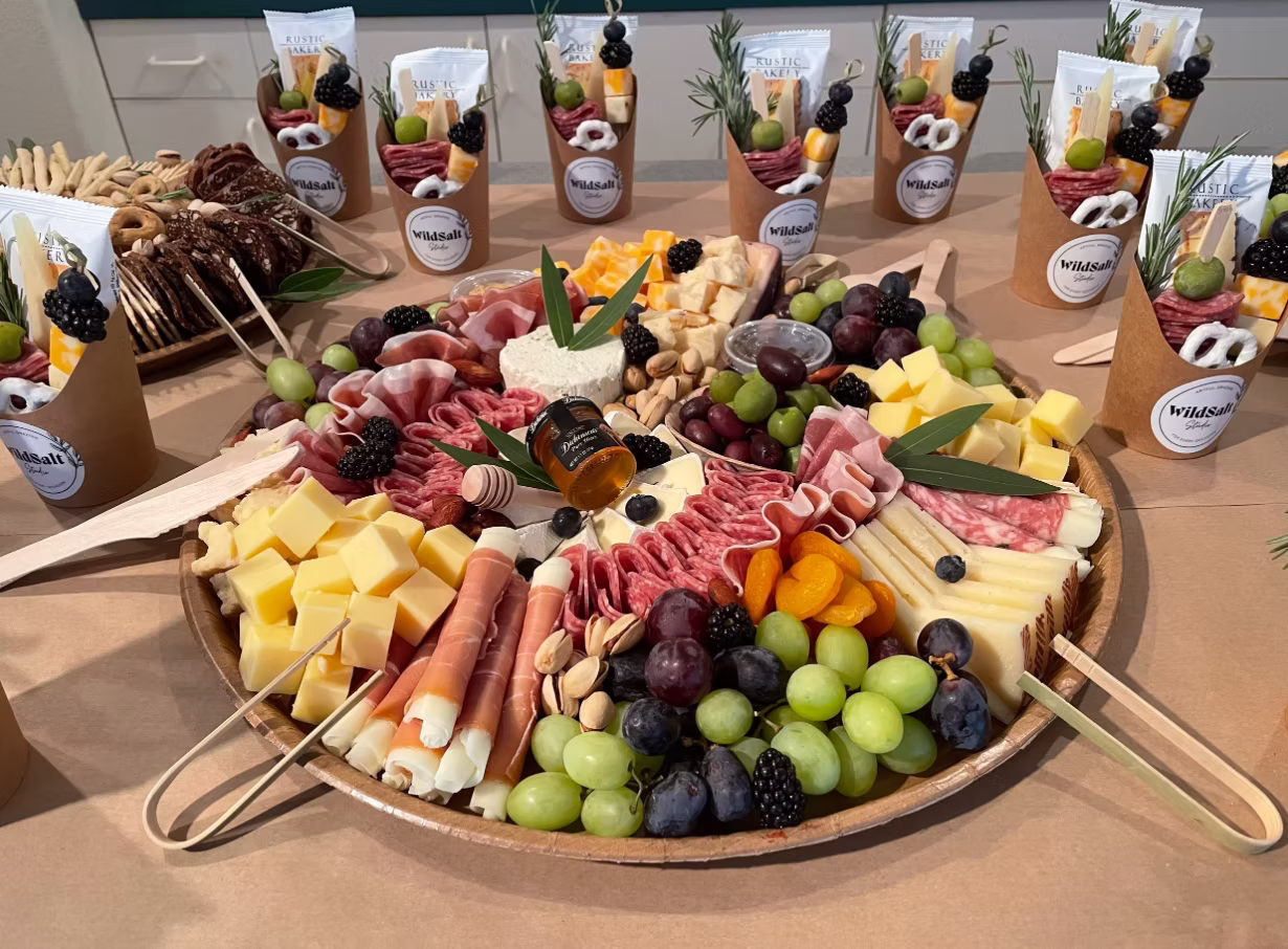 Charcuterie board by WildSalt Studio featuring cheeses, fruit, cured meats, and snacks served during a self-care community event.