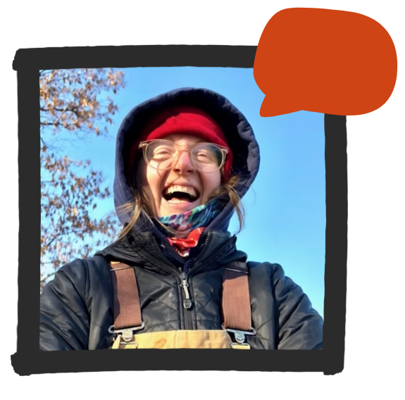 Podcast producer Caitlin Whyte smiling outdoors in cold weather gear, wearing glasses and a red beanie