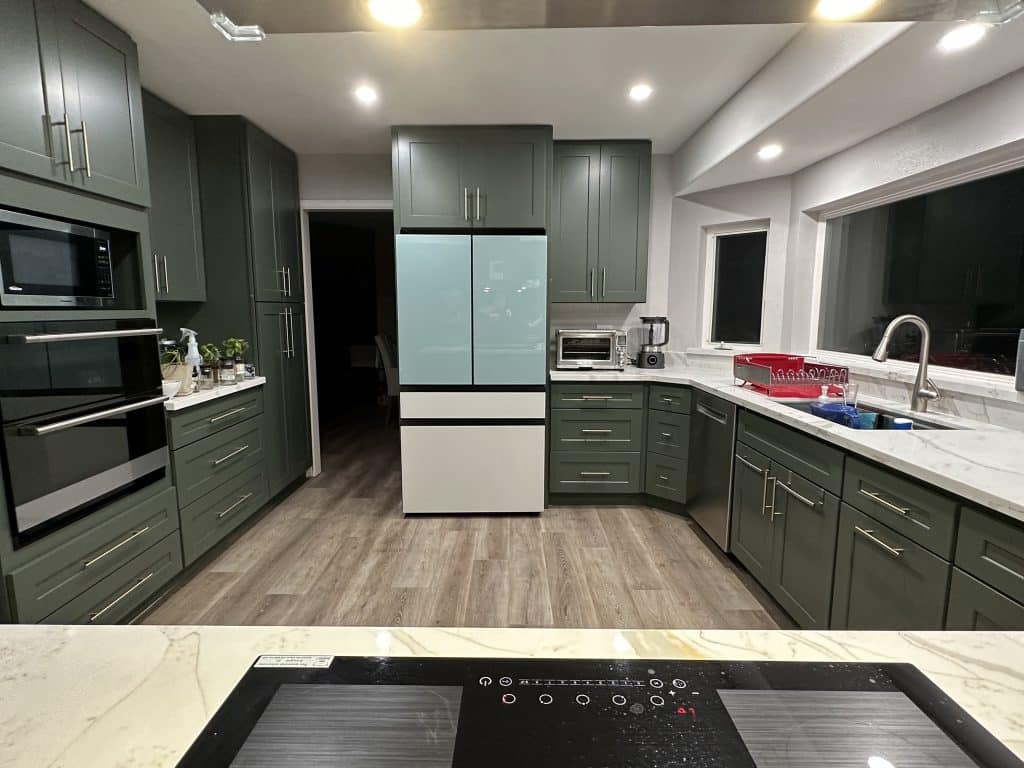 Green modern kitchen cabinetry with retro-style fridge and sleek hardware for a bold custom design.