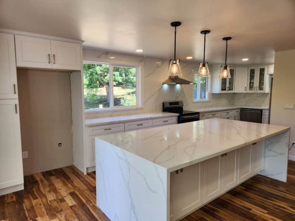 Modern kitchen remodel with white shaker cabinets, quartz island, and pendant lighting by Iconic Cabinetry.