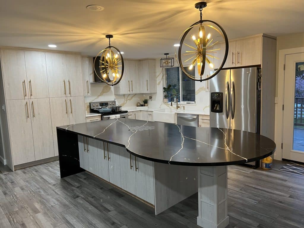Elegant kitchen remodel with curved island, glossy countertops, and dual statement pendant lights.