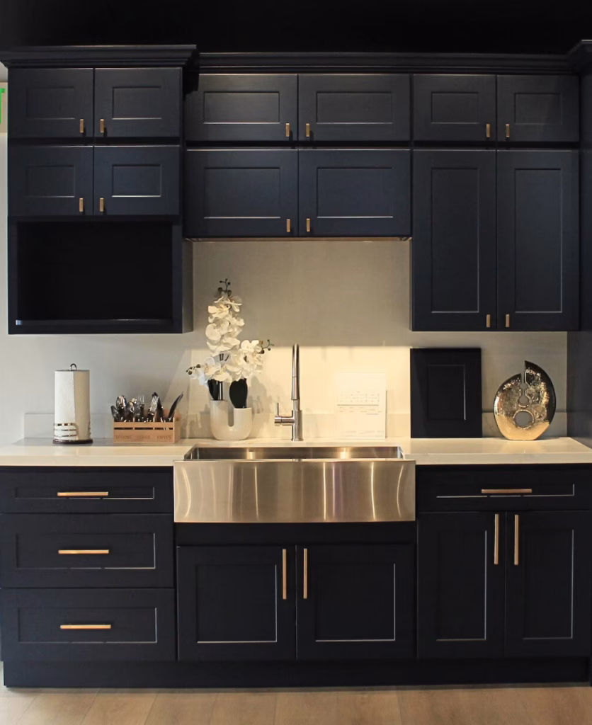 Navy blue shaker kitchen setup with farmhouse sink and brass hardware at Iconic Cabinetry showroom