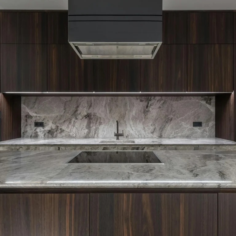 Modern kitchen countertop by Iconic Cabinetry featuring dark wood cabinetry, integrated sink, and gray marble backsplash