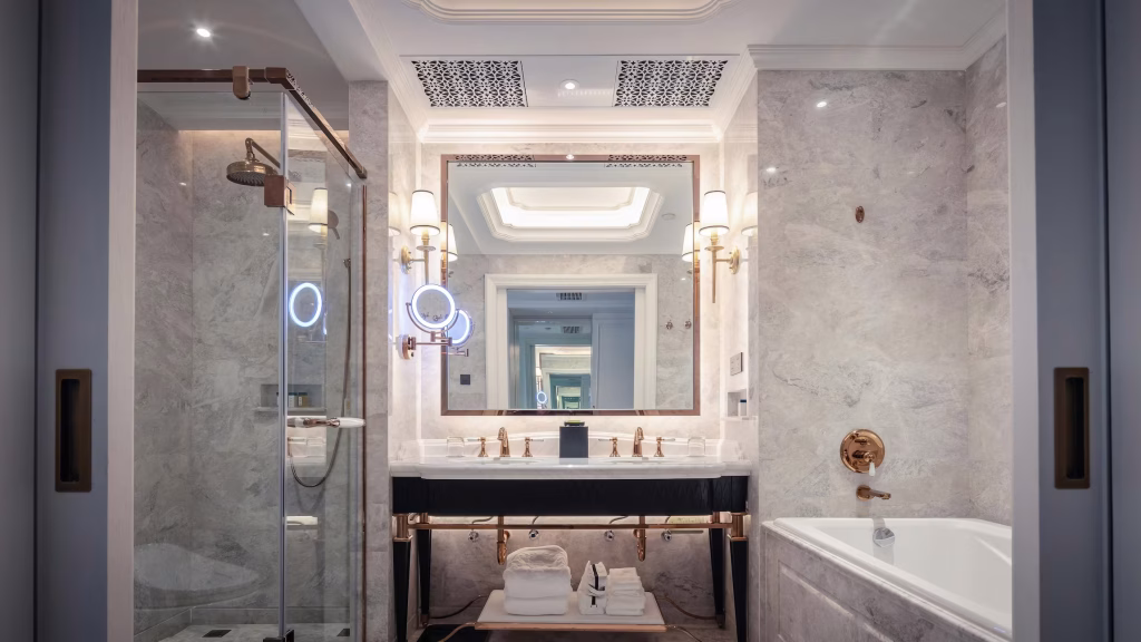 Elegant bathroom remodel with marble tile, gold fixtures, double vanity, and glass shower enclosure
