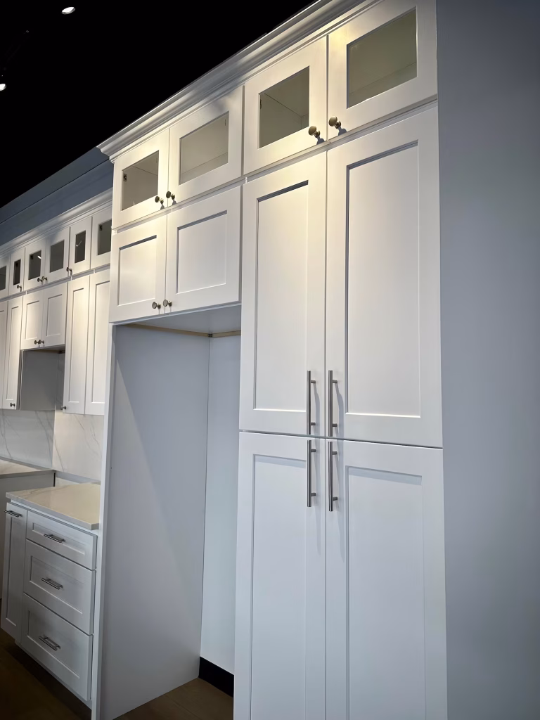 Spacious kitchen island and full wall of white shaker cabinets at Iconic Cabinetry showroom