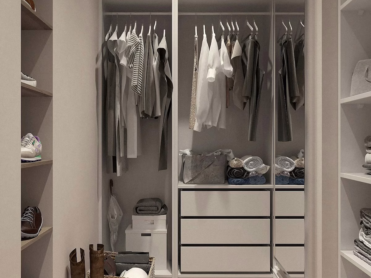 Modern walk-in closet with open shelving, hanging space, drawers, and herringbone wood flooring, featuring neutral-toned clothes and accessories neatly organized.