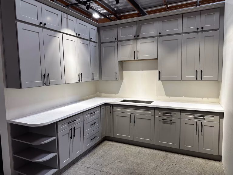 L-shaped kitchen with gray shaker cabinets and white countertops in Iconic Cabinetry showroom