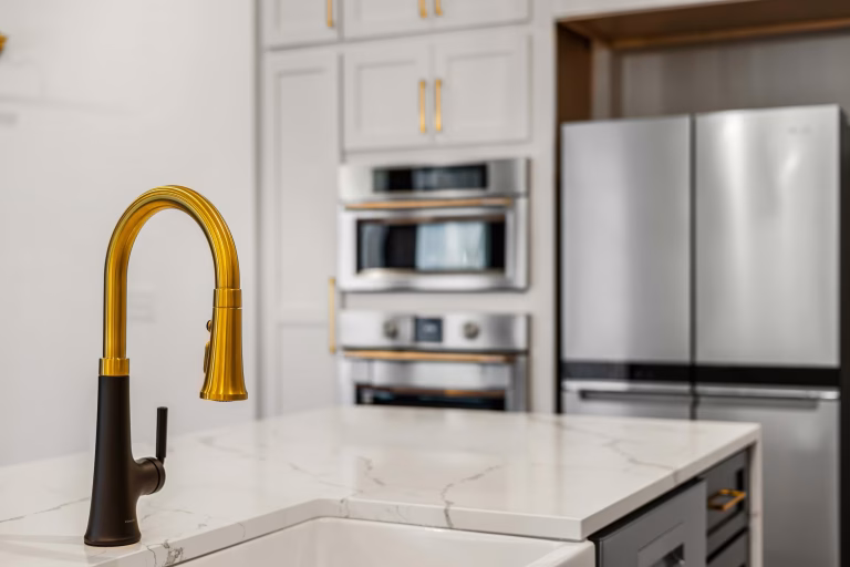 Updated galley-style kitchen with white cabinets, white countertops, and stainless steel appliances by Iconic Cabinetry