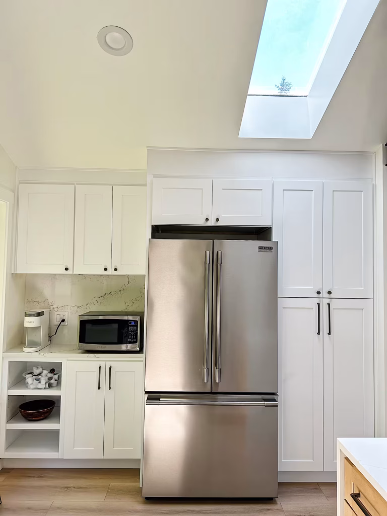 Kitchen with skylight, white shaker cabinets, and quartz countertops designed by Iconic Cabinetry