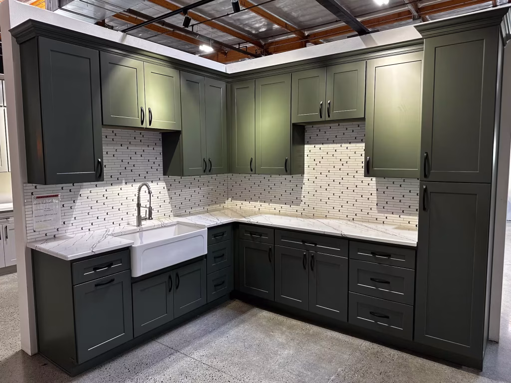 Green shaker kitchen with modern white tile backsplash and farmhouse sink from Iconic Cabinetry