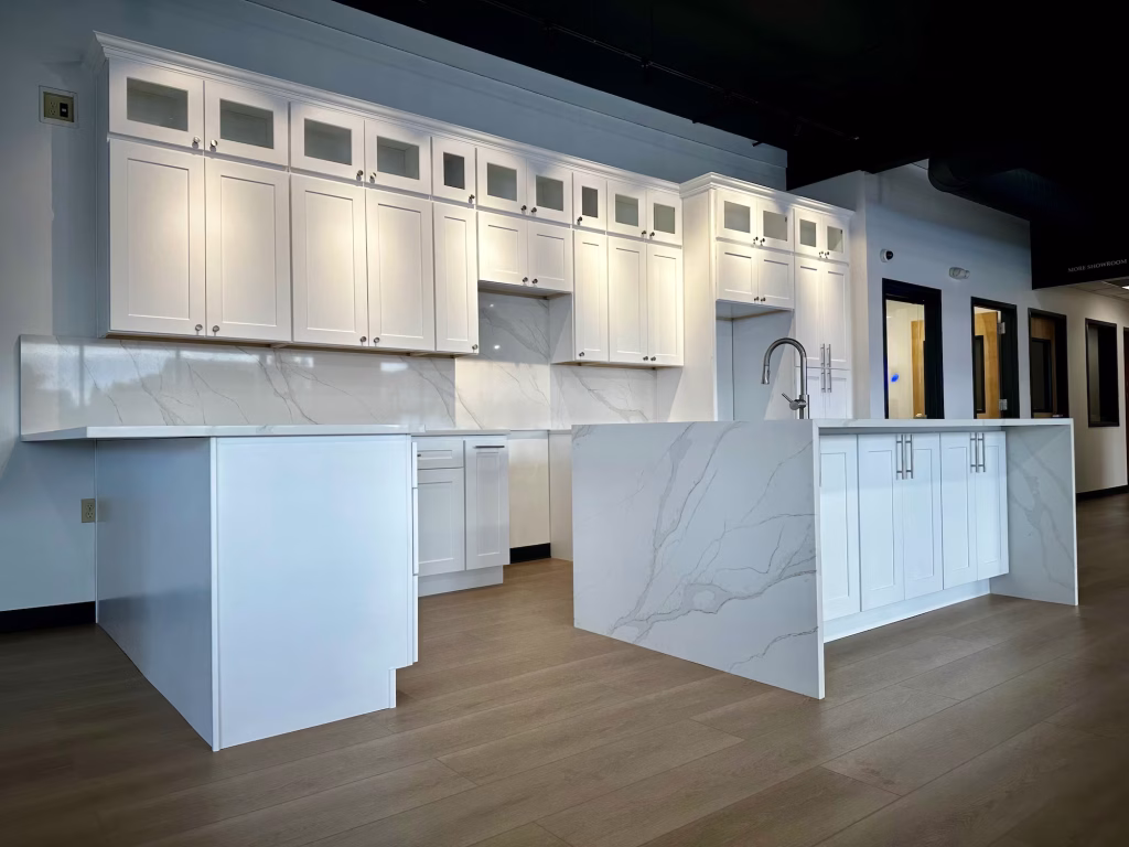 Close-up view of white shaker-style kitchen cabinets with glass upper panels at Iconic Cabinetry showroom