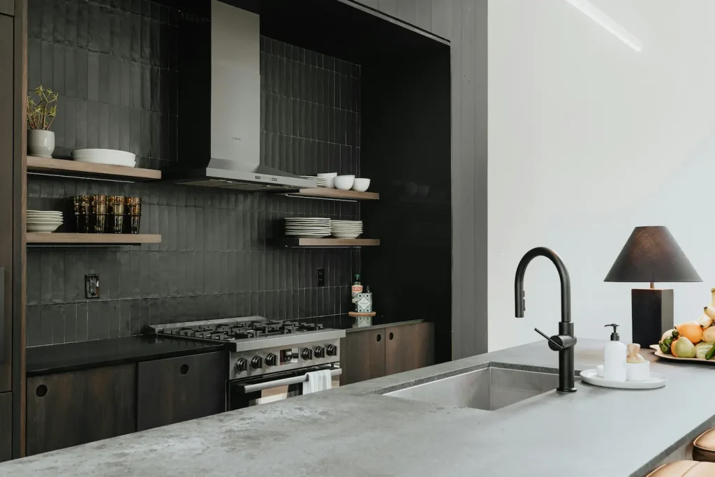 Modern black tile kitchen backsplash with open wood shelving and stainless steel range in a Seattle remodel