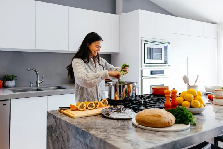 Seattle homeowner preparing food in a remodeled kitchen with white cabinets and marble island
