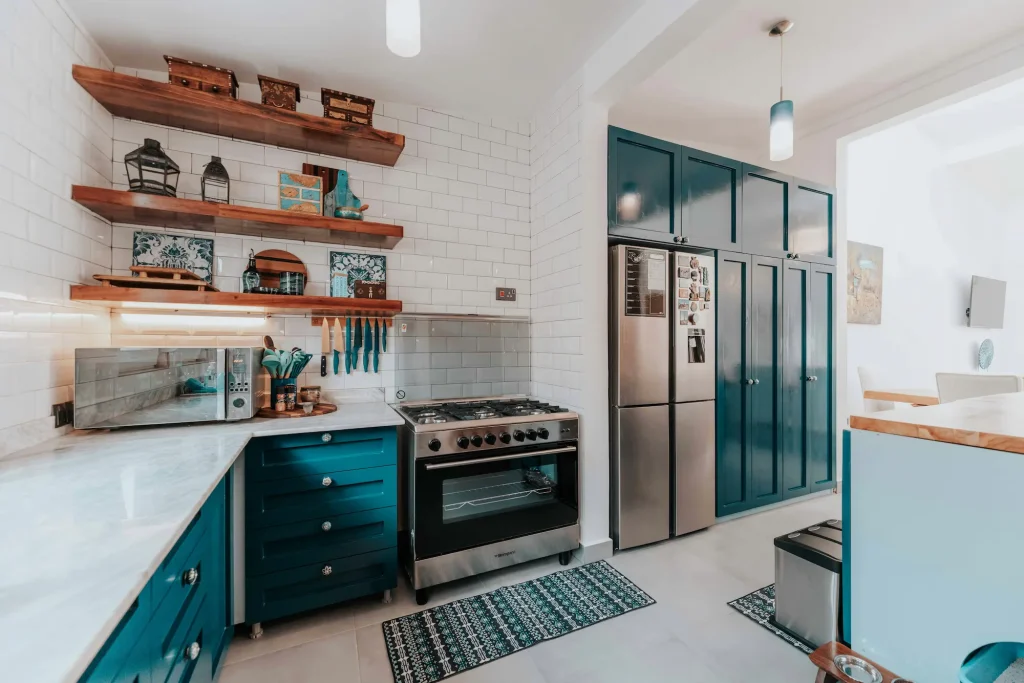Colorful kitchen with teal cabinetry and wood open shelving, blending modern personality with timeless design